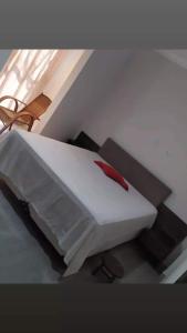 een wit bed met een rood kussen erop bij Sevili Garden Hotel in Arujá