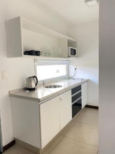 a white kitchen with a sink and a microwave at Mono Balcón Vista al Río Nª 304, Colonia del Sacramento in Colonia del Sacramento +4 photos