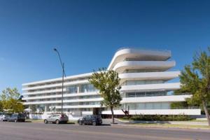 a white building with cars parked in front of it at Mono Balcón Vista al Río Nª 304, Colonia del Sacramento in Colonia del Sacramento
