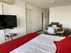 a bedroom with a bed and a tv and a table at Mono Balcón Vista al Río Nª 304, Colonia del Sacramento in Colonia del Sacramento