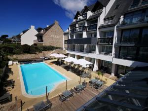 a swimming pool with chairs and umbrellas next to a building at Le Churchill Hôtel & Spa in Carnac