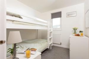 a bedroom with a bunk bed and a desk with a lamp at Bushwood-Beautifully Fitted Wooden Lodge Helston Cornwall in Helston