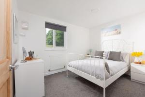 a white bedroom with a white bed and a window at Bushwood-Beautifully Fitted Wooden Lodge Helston Cornwall in Helston