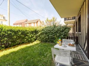 - une table et des chaises sur une terrasse couverte avec repas dans l'établissement Apartment Résidence du Port-2 by Interhome, à Cabourg