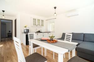 a kitchen and a living room with a table and a couch at Bodza Apartmanház in Harkány