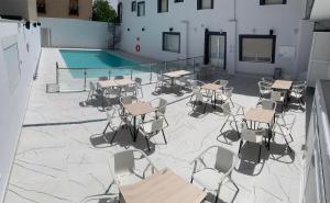 eine Terrasse mit Tischen und Stühlen sowie einem Pool in der Unterkunft Hostal La Paz in Ossa de Montiel