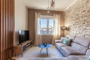 ein Wohnzimmer mit einem Sofa und einem TV in der Unterkunft Evangelia Residenza, elegant stay in Herakleion! in Iraklio