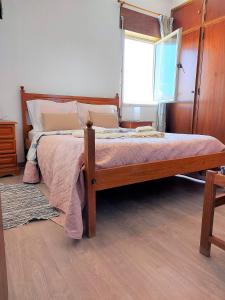 - une chambre avec un lit en bois et une fenêtre dans l'établissement Apartamento vista mar e pôr do Sol (1,6km Praia), à Aljezur 4 autres photos
