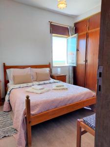 - une chambre avec un lit avec un cadre en bois et une fenêtre dans l'établissement Apartamento vista mar e pôr do Sol (1,6km Praia), à Aljezur