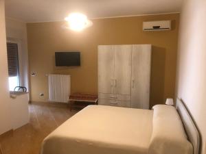 een slaapkamer met een bed, een kast en een televisie bij B&B Il Sogno in Montescaglioso