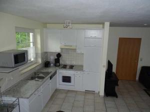 a kitchen with white cabinets and a sink and a microwave at Fewo Peenewiesen_SCHAe in Ostseebad Karlshagen