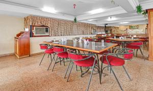 Treebo Trend Surya Yatri Niwas في بلغاوم: مطعم بطاولات خشبية وكراسي حمراء