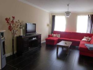 a living room with a red couch and a tv at Fewo Ostseetraum_JAeHN in Ostseebad Karlshagen