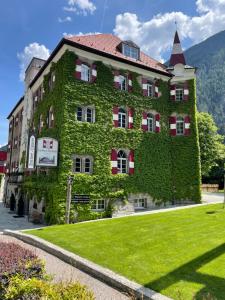a building covered in ivy with a lawn in front at Hotel Sachsenklemme in Fortezza