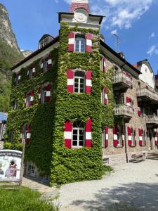 a building covered in ivy with a clock on it at Hotel Sachsenklemme in Fortezza