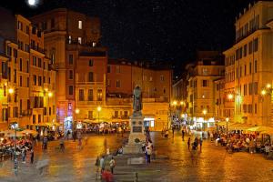uma rua da cidade à noite com uma estátua no meio em The Place - amazing loft in the heart of Rome em Roma
