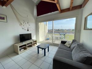 a living room with a couch and a tv at Le Tournesol in Mimizan