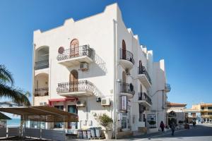 ein weißes Gebäude mit Balkon auf einer Straße in der Unterkunft DELPOSTO Marina di Ragusa DS in Marina di Ragusa