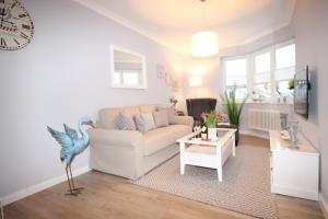 uma sala de estar com um sofá branco e uma mesa em KranichSuite - Zingst em Zingst