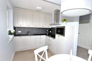uma cozinha com armários brancos, um lavatório e uma mesa em KranichSuite - Zingst em Zingst