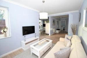 uma sala de estar com um sofá branco e uma televisão em KranichSuite - Zingst em Zingst