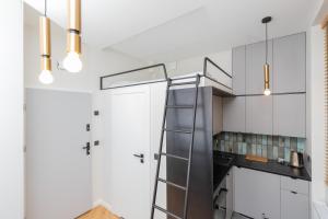 a kitchen with white cabinets and a spiral staircase at Nad Motlawa Apartamenty Seredynskiego by Renters in Gdańsk