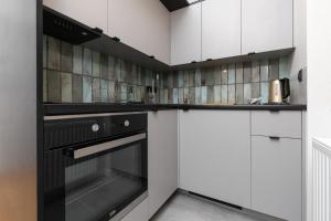 a kitchen with a black oven and white cabinets at Nad Motlawa Apartamenty Seredynskiego by Renters in Gdańsk