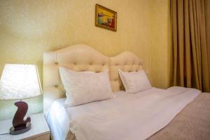 a bedroom with a white bed with a headboard and a lamp at HOTEL VLADi in Kutaisi