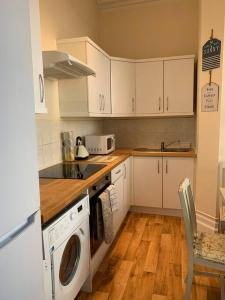 a kitchen with white cabinets and a washer and dryer at Bougainvillea in Ventnor