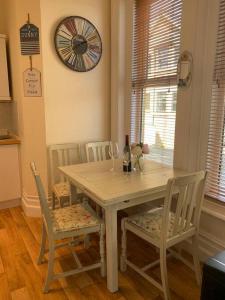 a dining room table with chairs and a clock on the wall at Bougainvillea in Ventnor