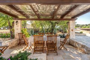 patio ze stołem i krzesłami pod pergolą w obiekcie Trullo La Succulenta w mieście Ceglie Messapica
