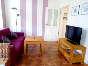 a living room with a purple couch and a tv at Ferienweingut Gansen / Hochgenuss 1 in Ernst