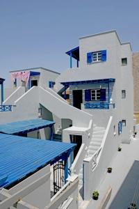 a large white building with blue windows and stairs at Lunar Santorini Hotel in Perissa
