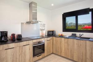 eine Küche mit Holzschränken und einem Fenster in der Unterkunft Tramontana quiet place 7 min from beach swimming pool bbq in Calenzana