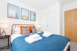 a bedroom with a blue bed with towels on it at Oxfordshire Living - The Tolkien Apartment - Oxford in Oxford