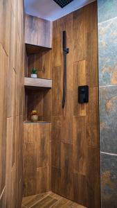 a bathroom with a shower with a wooden wall at House Proctor in Stoykite