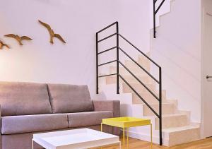 ein Wohnzimmer mit einem Sofa und einer Treppe in der Unterkunft Precioso duplex con patio junto a la Catedral in Cádiz