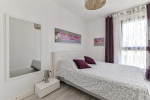 a white bedroom with a bed and a mirror at Appartement Glamour in Paris