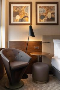 une chambre d'hôtel avec un lit, une chaise et une table dans l'établissement Crowne Plaza Geneva, an IHG Hotel, à Genève