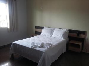 1 dormitorio con 1 cama con sábanas blancas y almohadas blancas en HOTEL QUALITY, en Parauapebas