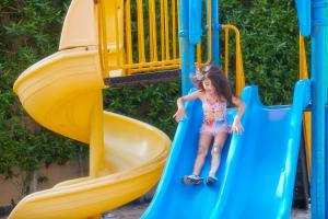 a little girl sliding down a slide on a playground at Bahi Ajman Palace Hotel in Ajman 