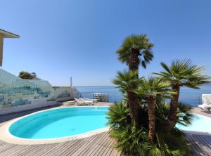 a swimming pool with palm trees on a deck at La Rosa Sul Mare in Siracusa