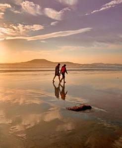 Dos personas caminando por la playa al atardecer en The Nook, en Tawnyinah