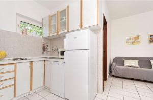 eine Küche mit einem weißen Kühlschrank und einem Sofa in der Unterkunft Apartments and Room Lotus in Tribunj