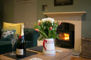 Una botella de champán y un jarrón de flores sobre una mesa. en Glyn Y Coed, Mumbles, en Newton