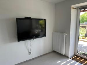 TV de pantalla plana colgada en una pared blanca en Apartament Połaniecka 1B/2 en Zielona Góra