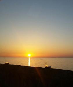 a sunset on the beach with a boat in the water at Gallipoli Mancaversa Futura Vacanza Andrea in Marina di Mancaversa