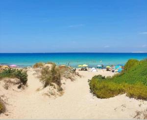 a beach with umbrellas and people in the water at Gallipoli Mancaversa Futura Vacanza Andrea in Marina di Mancaversa