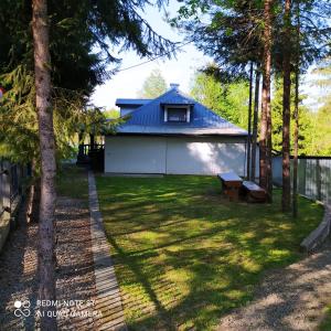 a backyard with a white building and trees at Zacisze in Hołuczków