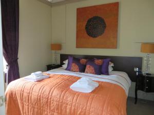 a bedroom with a large bed with towels on it at Hewlett Apartments in Cheltenham
